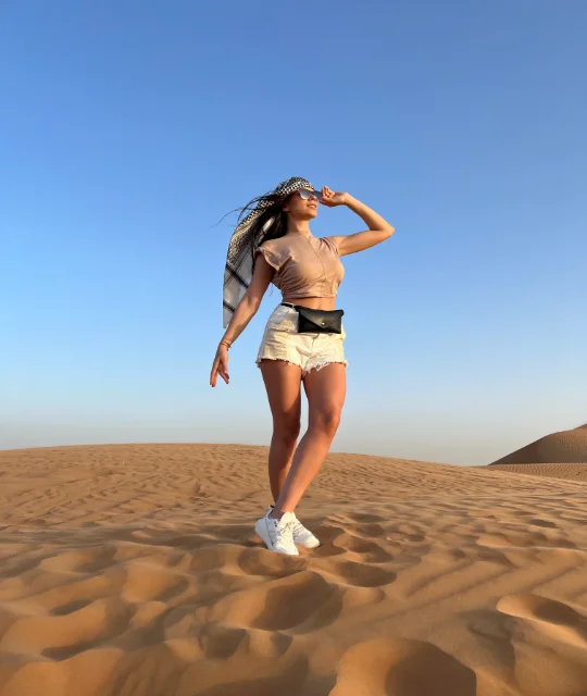 Female taking a picture in middle of desert on a dune buggy adventure in dubai