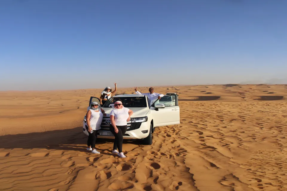 group of people taking a photo with land cruiser in dubai's desert