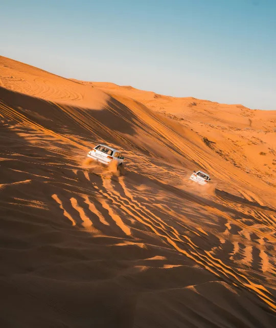 cars sliding down dunes in dubai desert safari with desert thrill